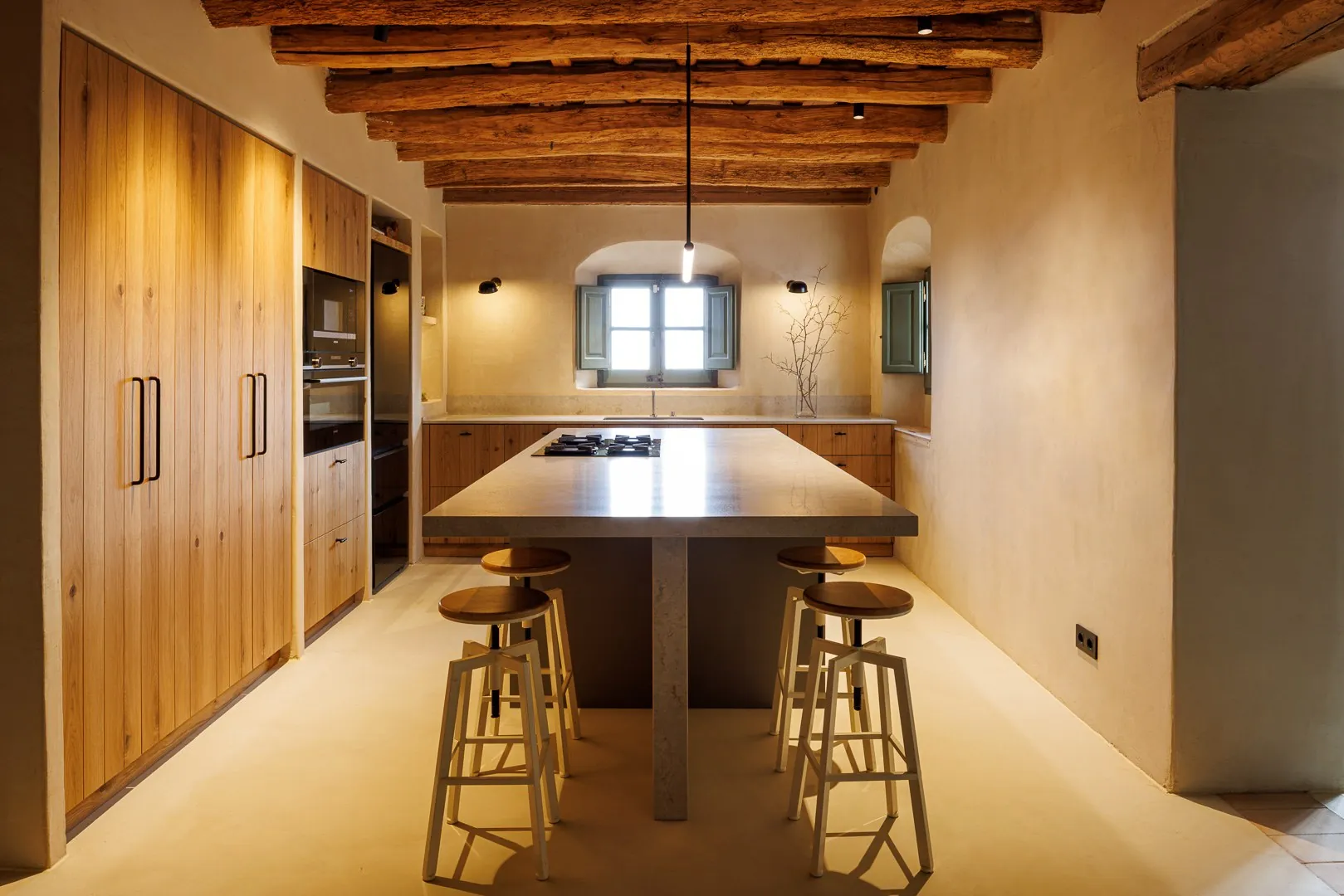Cocina Auró en el proyecto Alella: armarios de madera e isla bajo las vigas