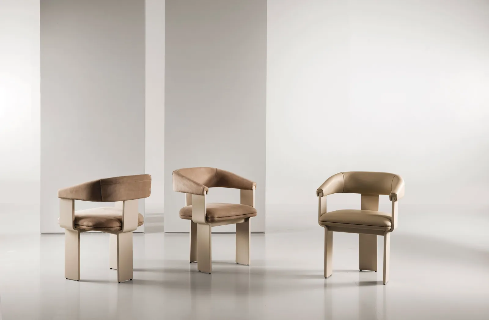 Tres sillones Emmemobili tapizados en piel con respaldo curvado.