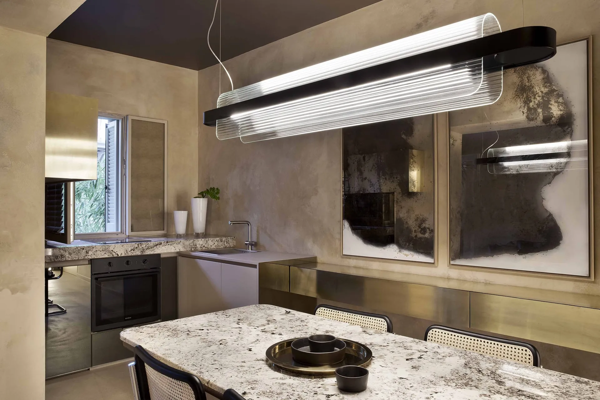 Nami linear pendant with fluted glass above a stone table in Casa Brag